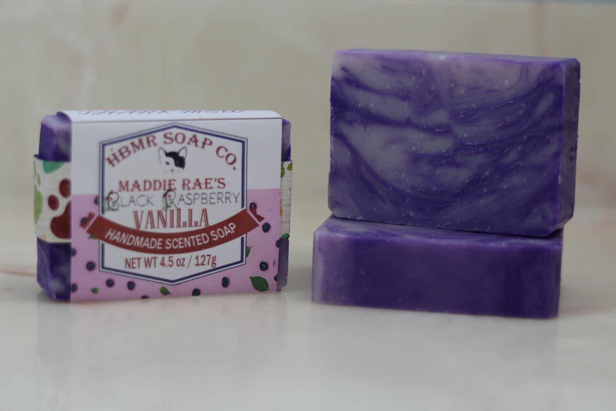 Purple soap bar and packaging with 'HBMR Soap Co.' branding on a light background