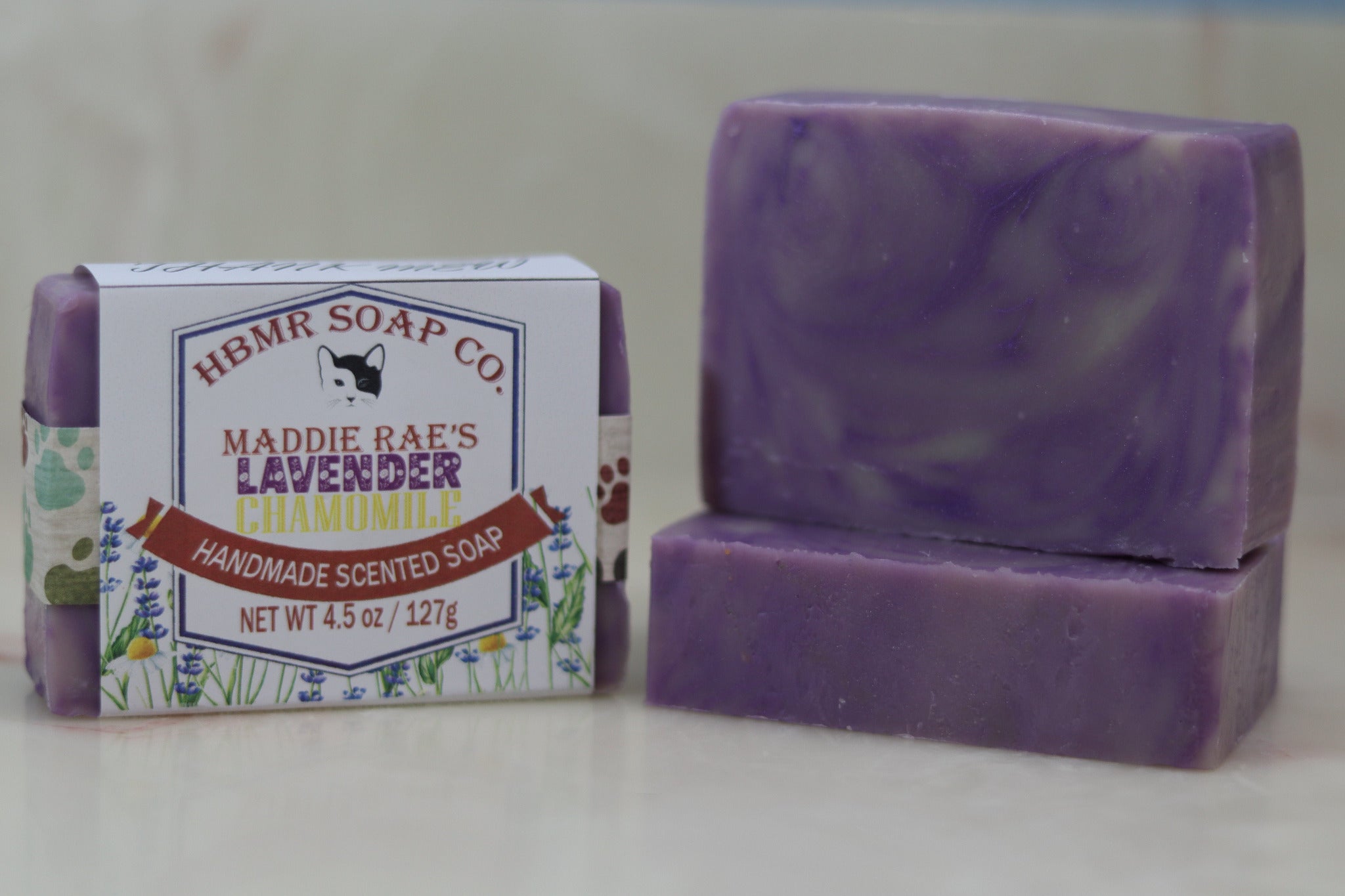 Purple soap bar with packaging labeled 'HBMR Soap Co. Maddie Rae's Lavender Chamomile' on a light background