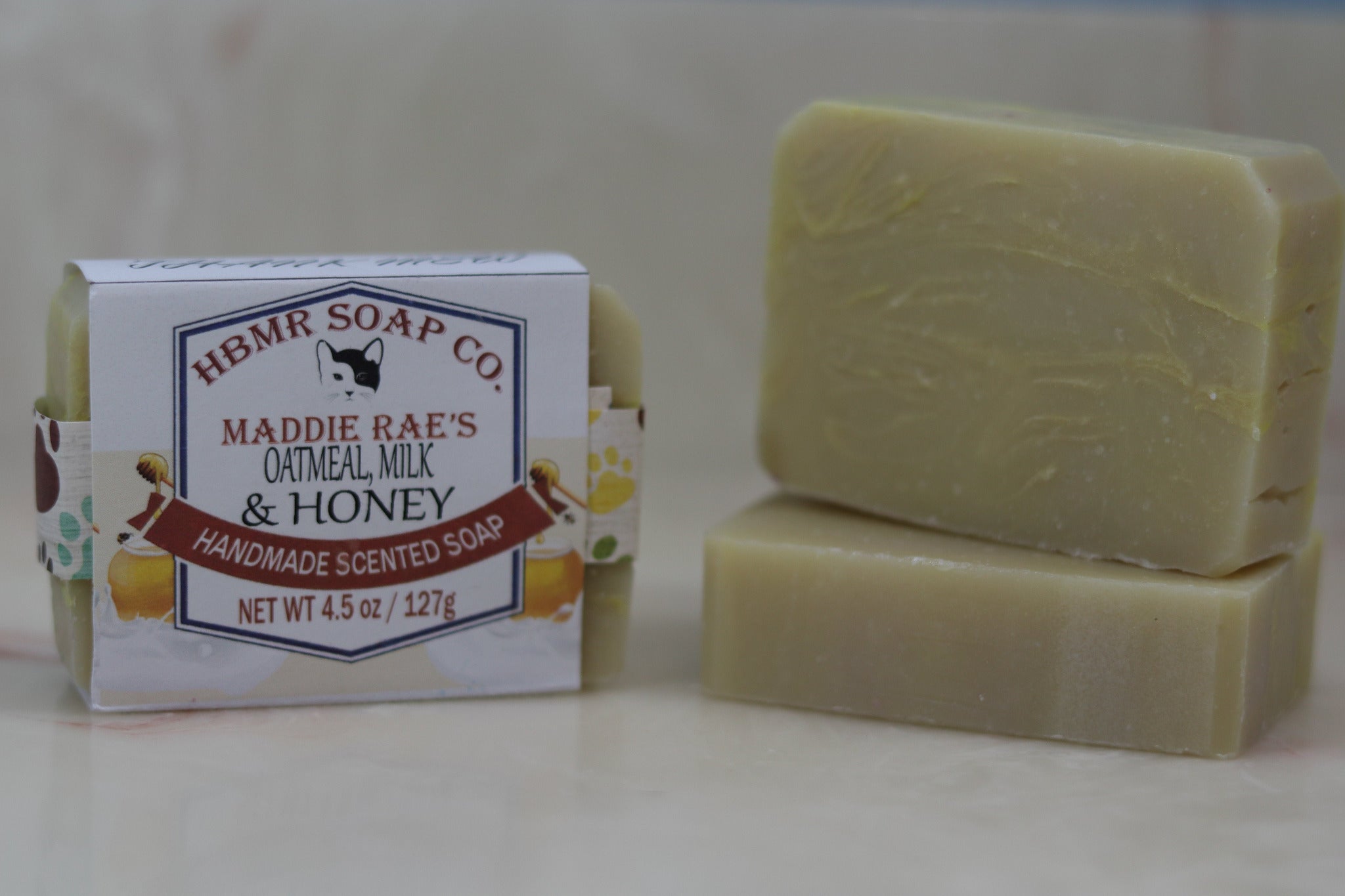 Two bars of soap and their packaging with 'HBMR Soap Co.' branding on a light background.