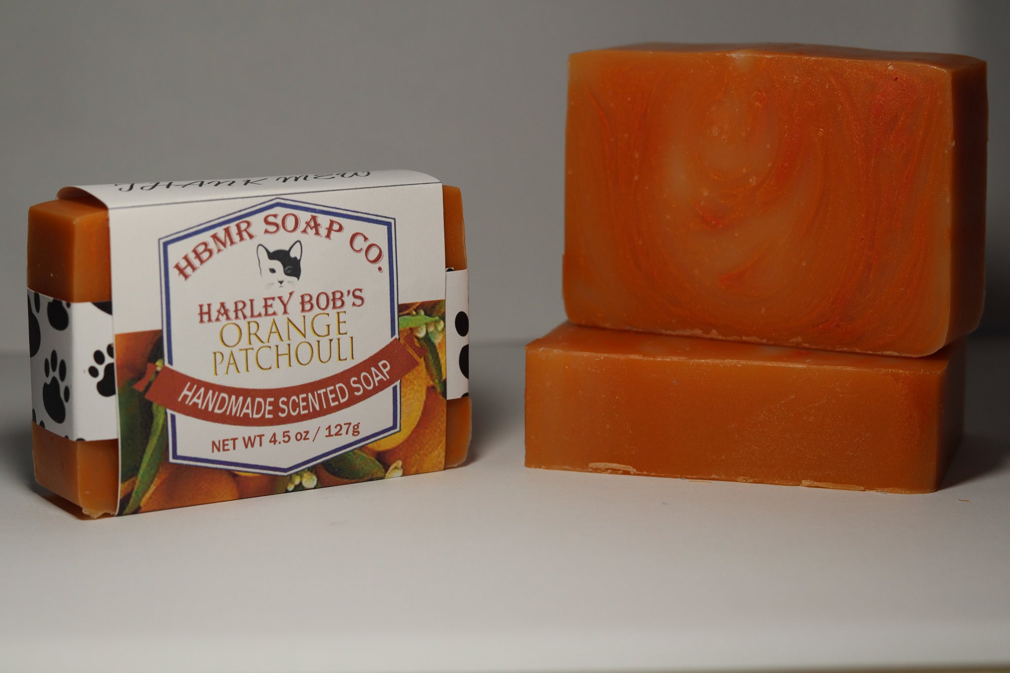 Two bars of orange soap with a box labeled 'Harley Bob's Orange Patchouli' on a gray background