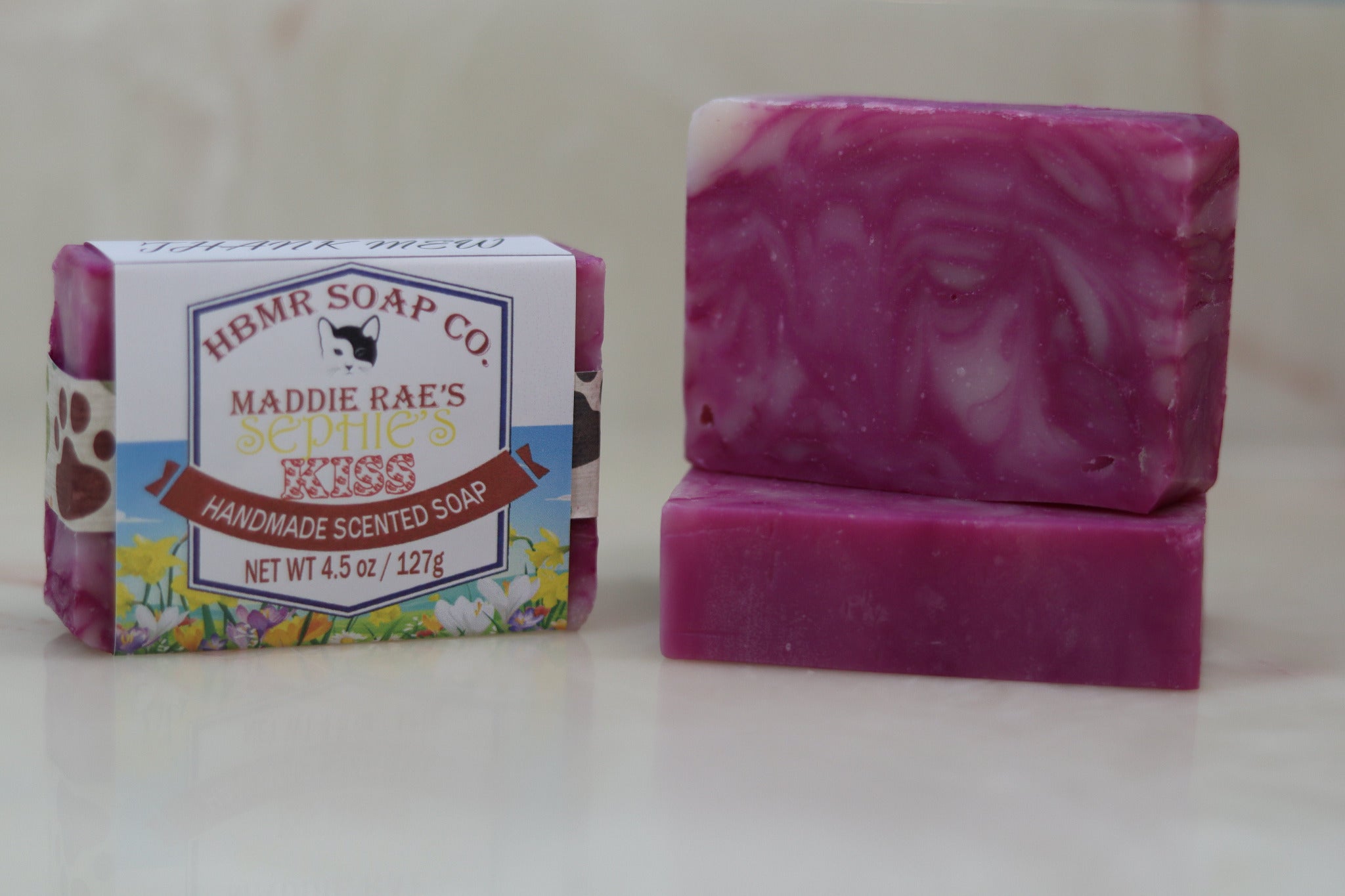 Two bars of pink soap with a HBMR Soap Co packaging on a light background