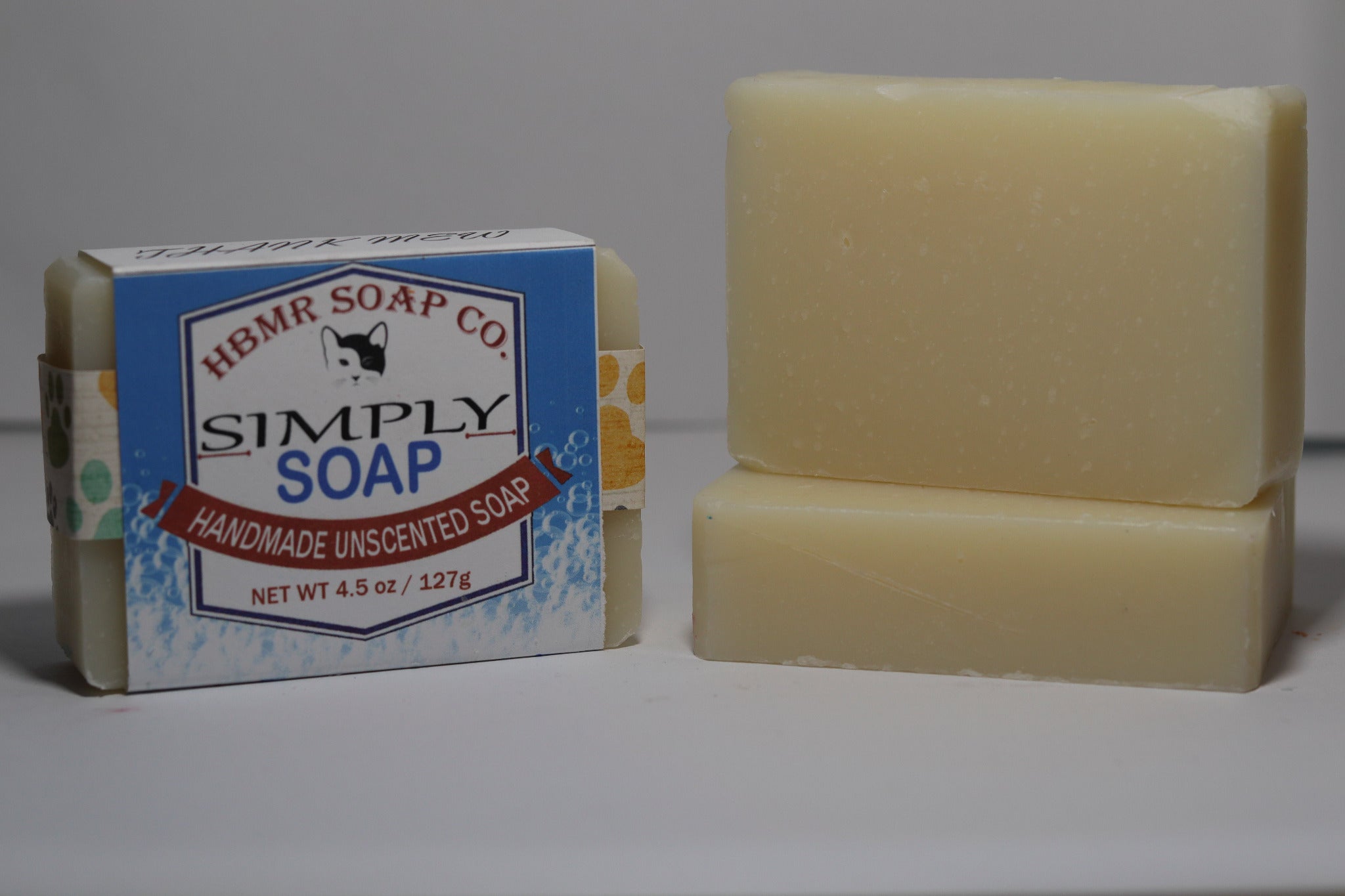 Two bars of soap, one with packaging, on a plain background